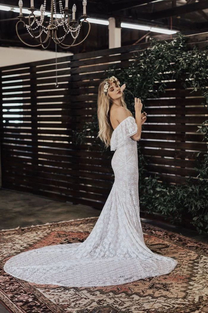 beaded wedding dresses woman with long blonde wavy hair floral crown wearing dress made of lace with long lace train