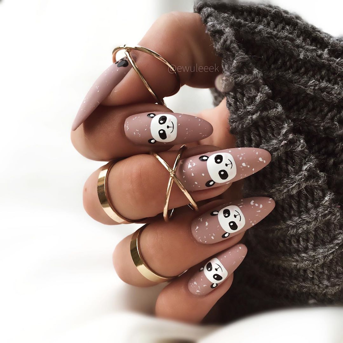 beige nude nail polish with white panda decorations on each nail short nail designs long almond nails gold rings on each finger