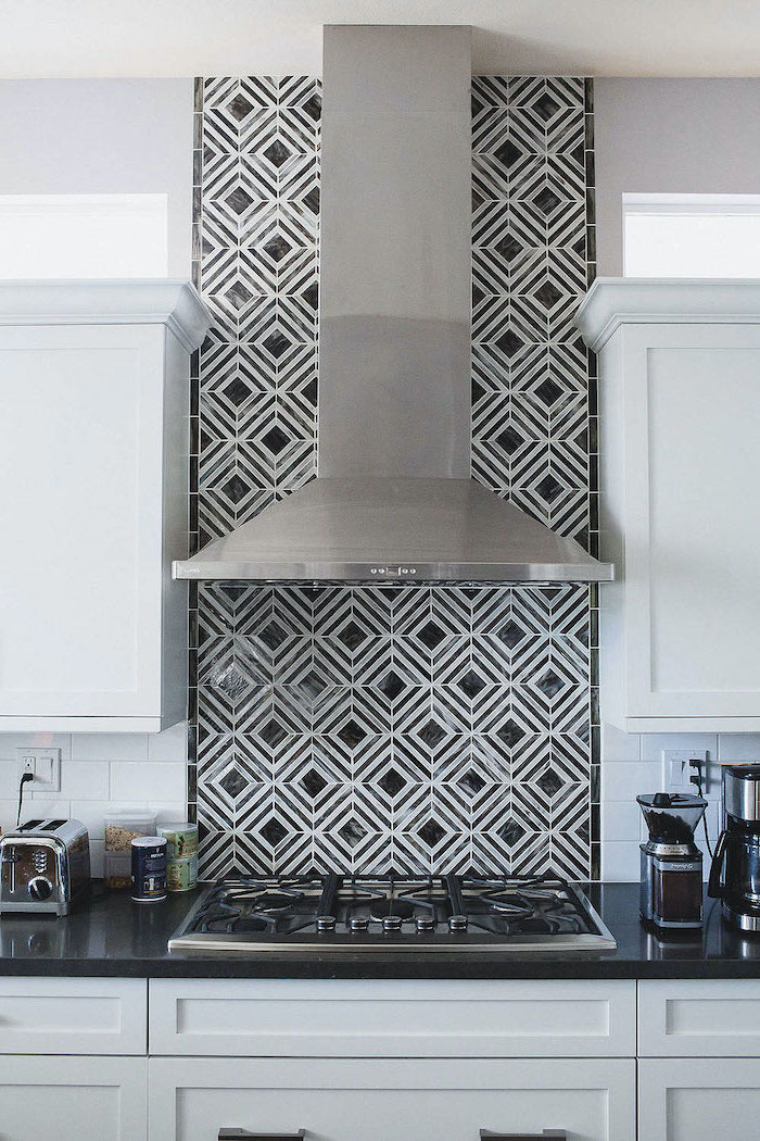 black and white patterned tiles behind the kitchen hood above the stove kitchen backsplash tile white cabinets with black countertop