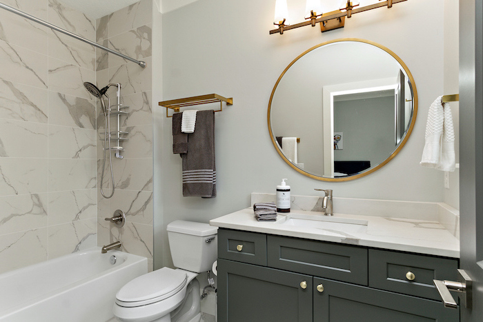 black cabinet with marble countertop round mirror above it bathroom picture ideas white bathtub with shower with marble tiles