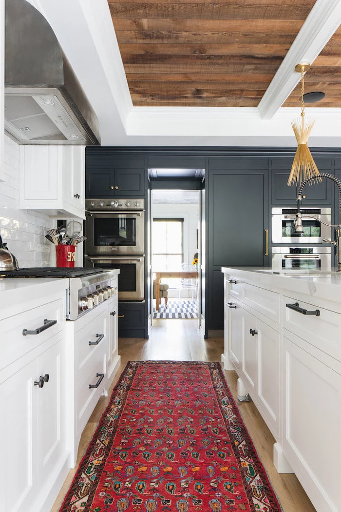 black cabinets on one side white cabinets white subway tiles backsplash rustic farmhouse kitchen colorful carpet on wooden floor
