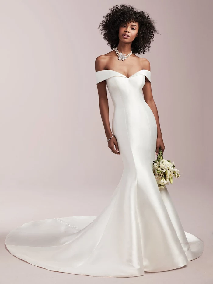 black curly hair on woman wearing long satin dress with train short sleeve wedding dress holding a bouquet