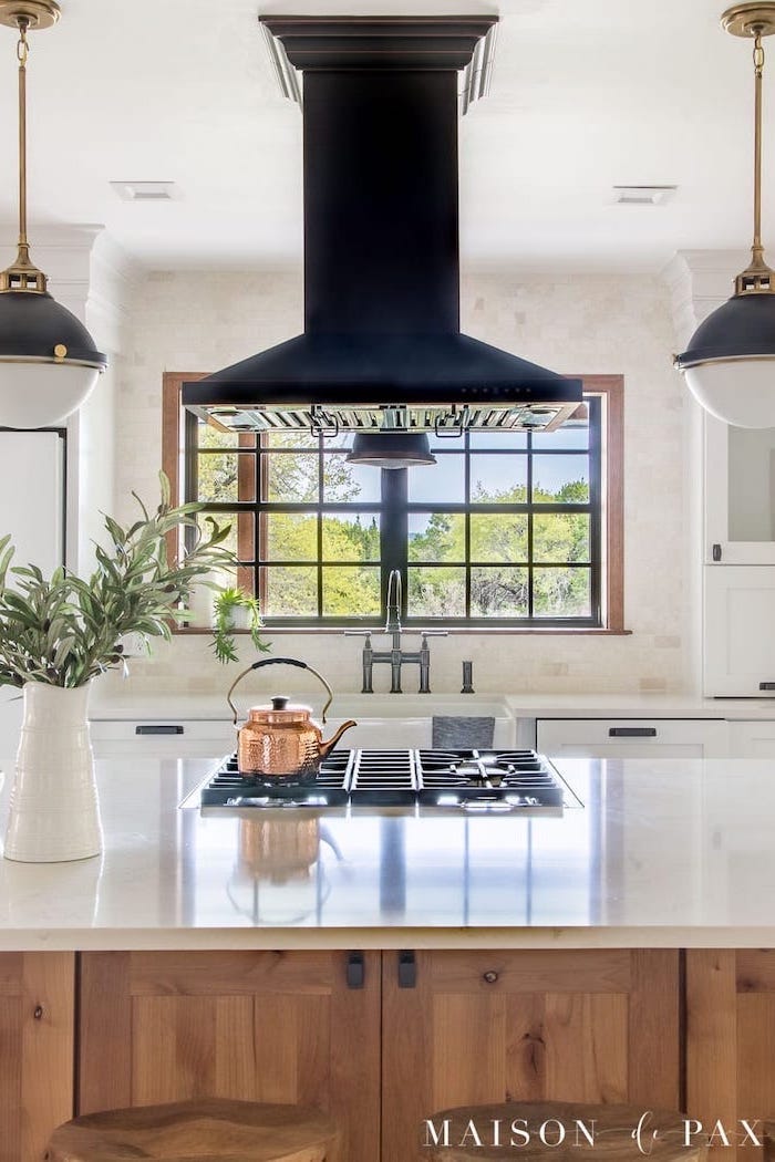 black fixtures above wooden island with white countertop modern farmhouse kitchen decor white tiles on the wall