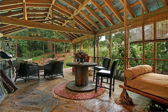 black garden chairs black bar stools around wooden table screened in patio with cathedral ceiling stone floor
