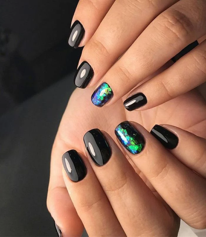 black nail polish multi colored nails green blue purple decorations on ring finger on each hand short squoval nails