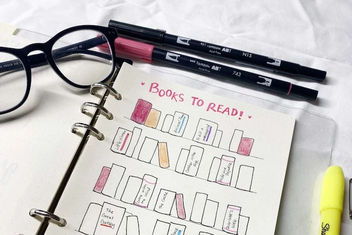 books to read spread with books drawn on the white notebook bullet journal pinterest glasses and markers around it