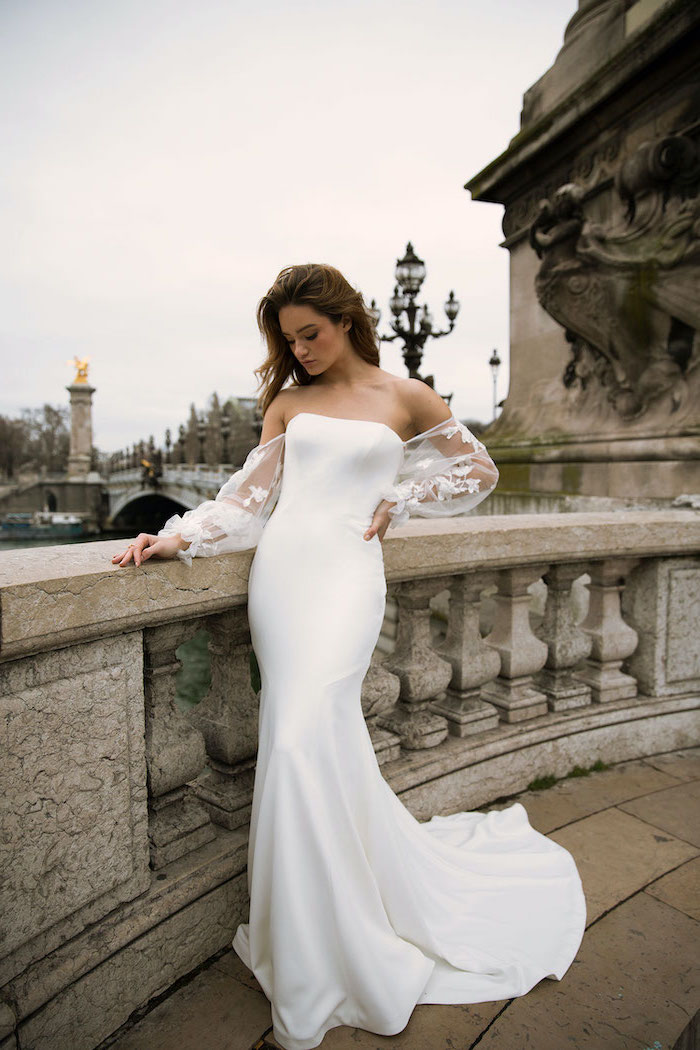 bridge over a river short sleeve wedding dress woman standing on it wearing long dress with tulle long sleeves