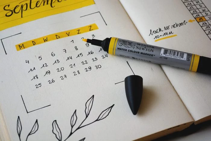bullet journal themes calendar for september written in black and colored in yellow on white notebook