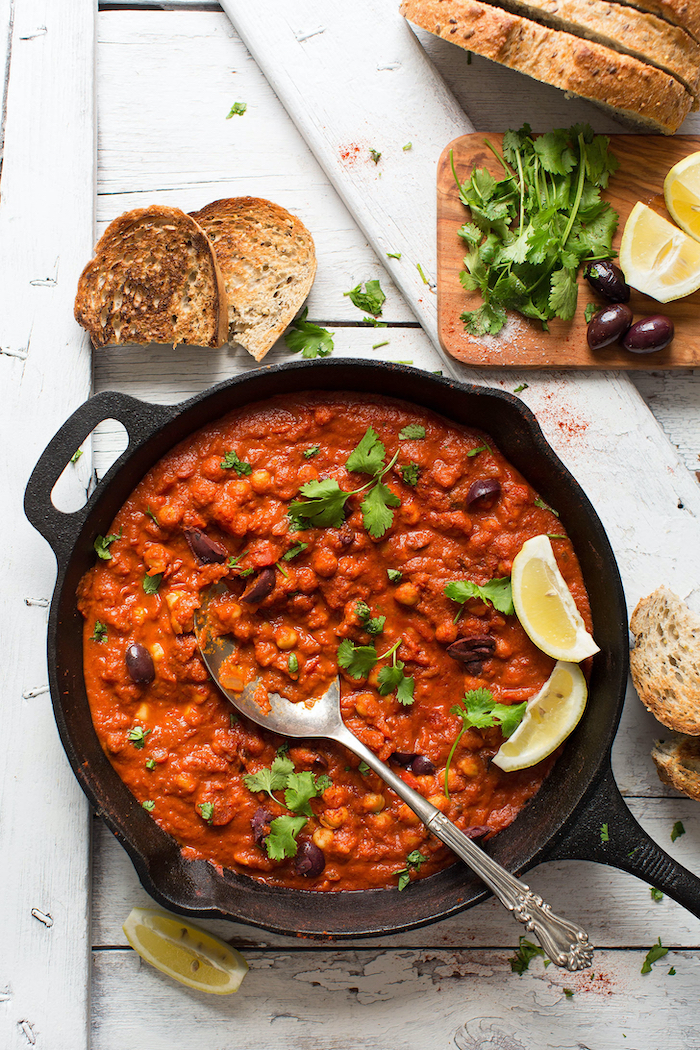 chickpea shakshuka with tomato sauce cooked in skillet canned chickpea recipes garnished with olives lemon and parsley