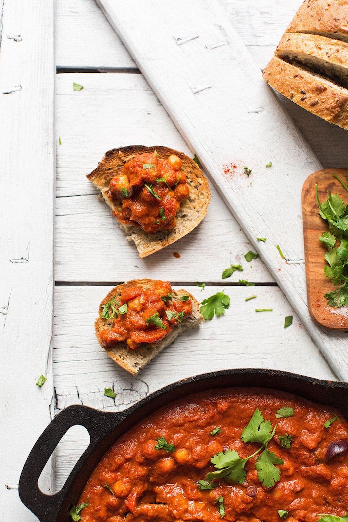 chickpea shakshuka with tomato sauce cooked in skillet canned chickpea recipes placed on white wooden surface