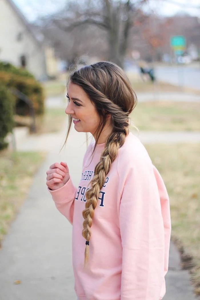 easy hairstyles for long hair brunette girl with blonde ombre hair in long side braid wearing pink varsity sweatshirt