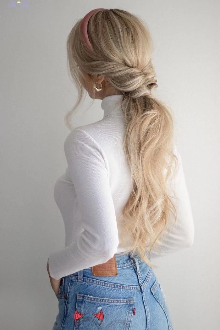 easy hairstyles for short hair woman with long blonde wavy hair half braded in small ponytail wearing white polo blouse jeans