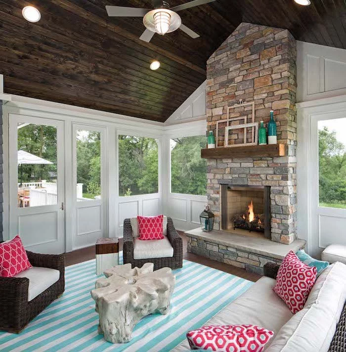 fireplace made of stone screened in deck wooden cathedral ceiling turquoise and white striped carpet red throw pillows