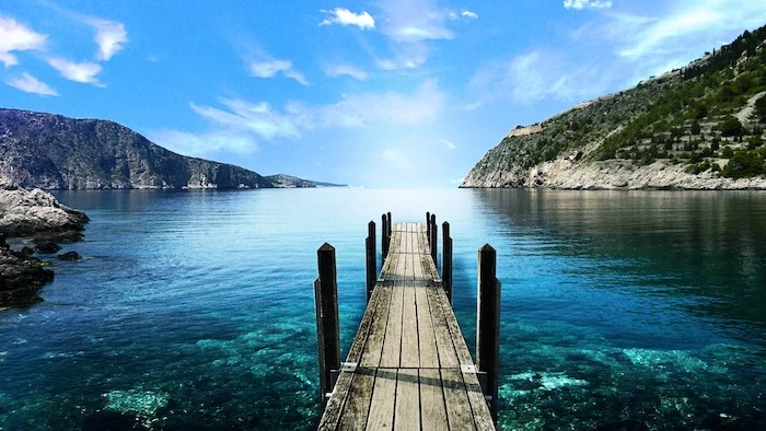 free wallpaper for computer wooden pier leading to a lake with turquoise water surrounded by hills