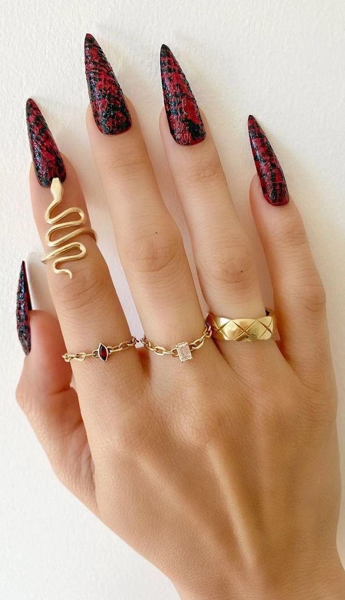 gold rings on fingers with long stiletto nails simple nail designs black and red snake skin print on the nails
