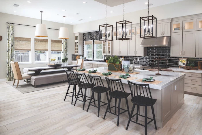 gray wooden kitchen island with marble countertop black stools farmhouse kitchen backsplash with black tiles white cabinets