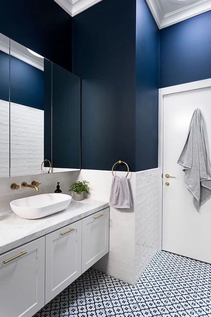 how to decorate a bathroom dark blue walls with white tiles at the bottom black and white patterned tiles on the floor floating white cabinet with marble countertop