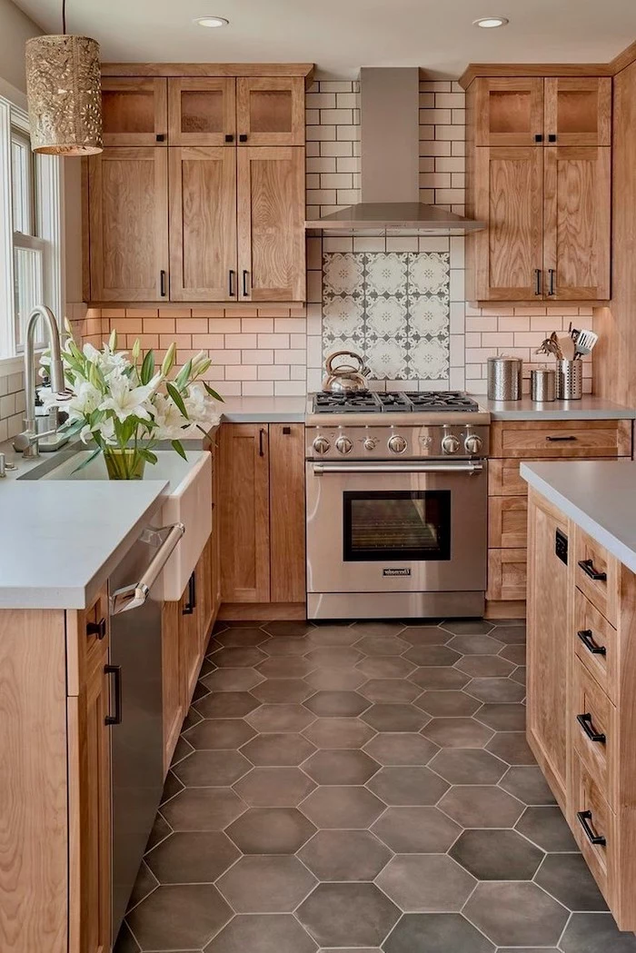 kitchen backsplash tile in white patterned tiles above the stove woooden cabinets and kitchen island with white countertops