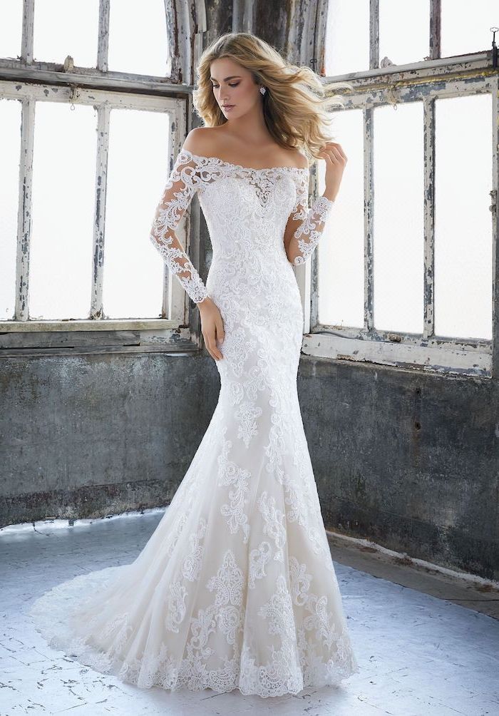 long sleeve lace wedding dress blonde woman standing in front of windows wearing long dress made of lace