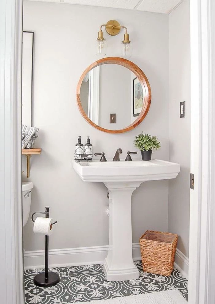 mirror with wooden frame above vintage sink black and white patterned tiles on the floor bathroom decor pictures white walls