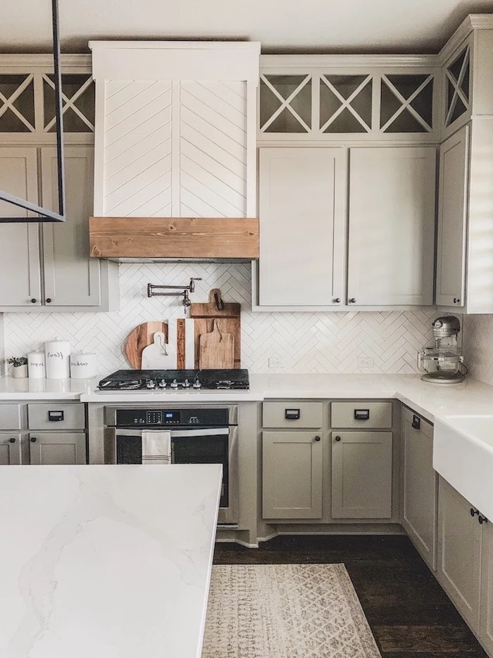 modern farmhouse kitchen light gray cabinets with white countertop and tiled backsplash dark wooden floor kitchen island