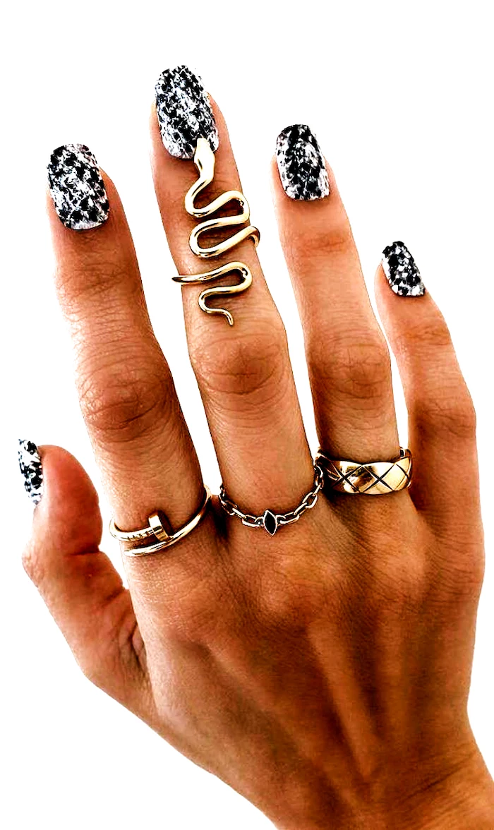multi colored nails black and white snake skin print decorations on medium length almond nails gold rings on fingers