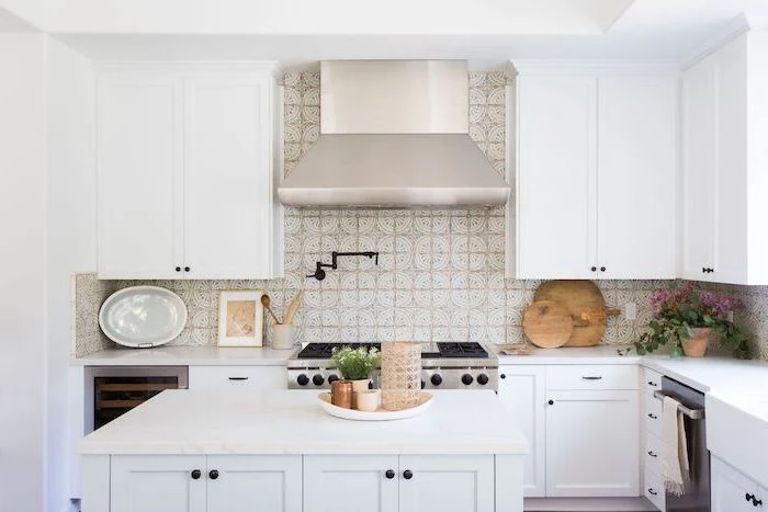 patterned tiles above the stove in white and beige subway tile backsplash white cabinets and kitchen island with white countertops