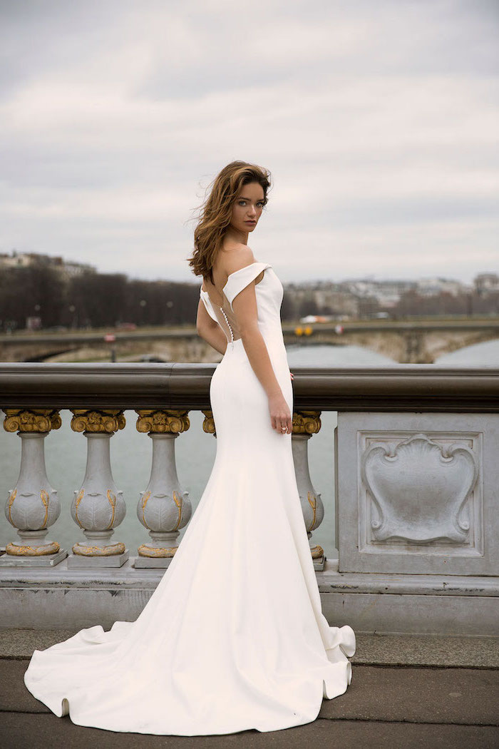 short sleeve wedding dress woman with dark blonde hair standing on an old bridge wearing white dress with medium train