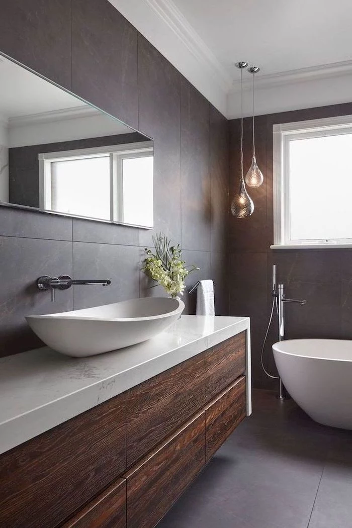 small bathroom remodel floatin wooden cabinet with marble countertop dark tiles on the walls and floor white bathtub