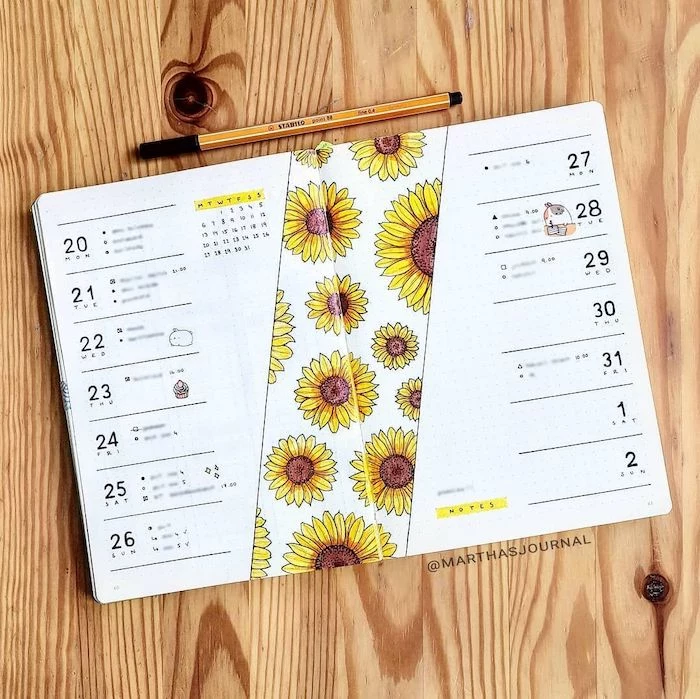 sunflowers drawn on white notebook with separate lines for each day of the month bullet journal ideas placed on wooden surface