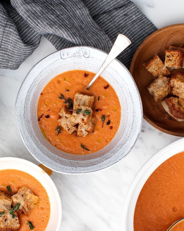 tomato soup with chickpeas hummus from dried chickpeas garnished with herbs and crouotons with melted chees inside ceramic bowl