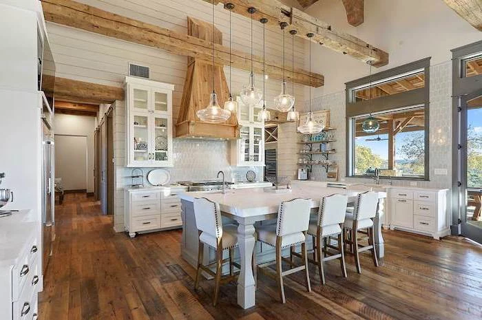 white kitchen island with white leather stools rustic farmhouse kitchen exposed wood beams on cathedral ceiling dark wooden floor