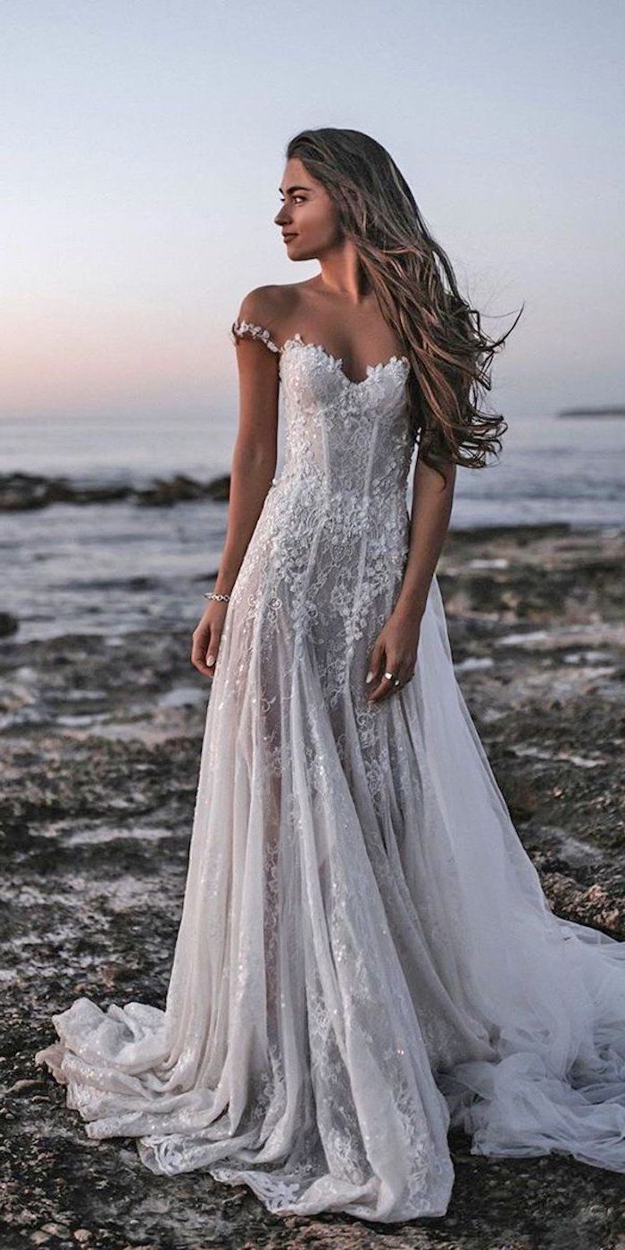 woman standing on the beach with long wavy dark blonde hair off the shoulder wedding dress with lace and tulle