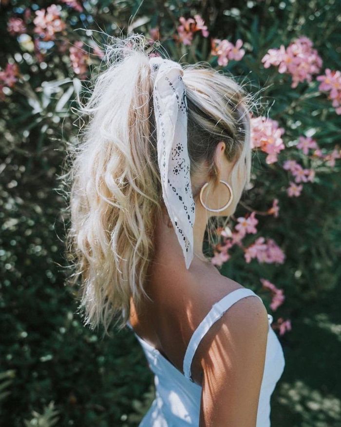 woman with long blonde wavy hair tied in a high ponytail with white silk scarf easy hairstyles for long hair wearing white dress