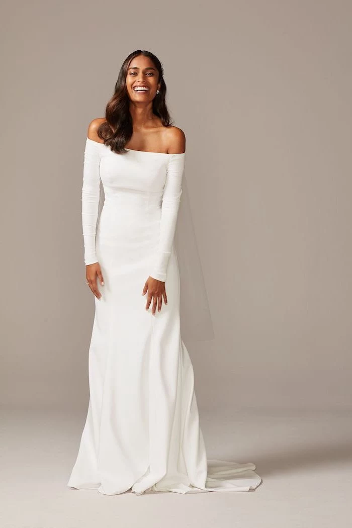 woman with medium length brown wavy hair wearing off the shoulder wedding dress white with long sleeves