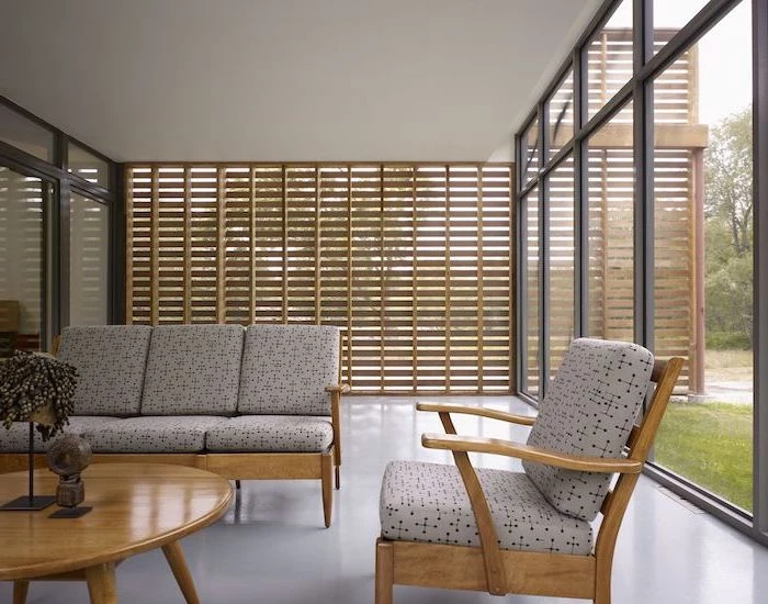 wooden blinds and tall windows screened in patio wooden living room furniture with light gray cushions