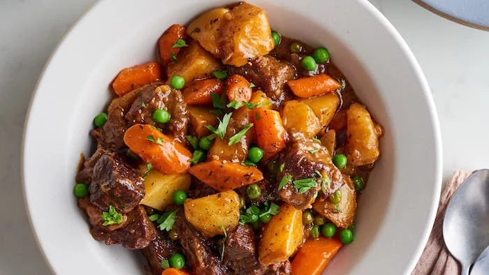 beef stew cooked in instant pot with potatoes carrots peas garnished with chopped parsley instant pot dinner recipes