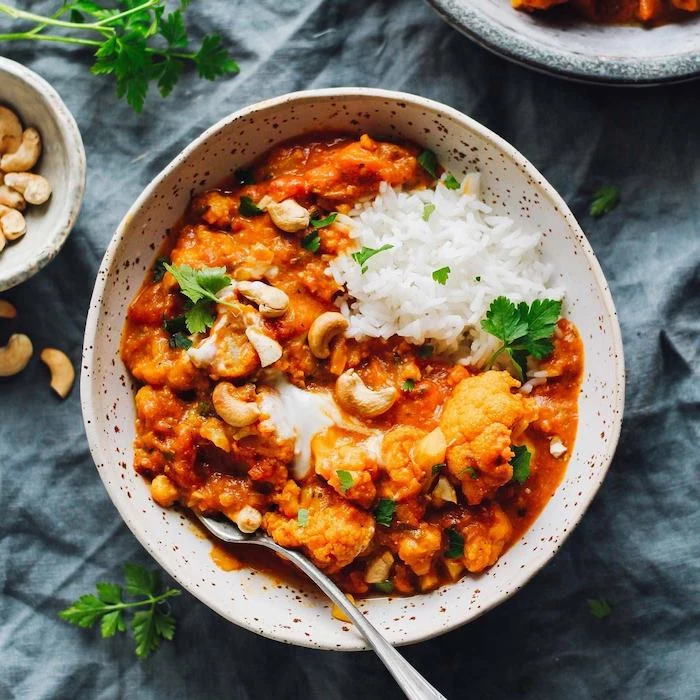 best instant pot recipes cauliflower tikka masala curry with white rice garnished with parsley inside white ceramic bowl