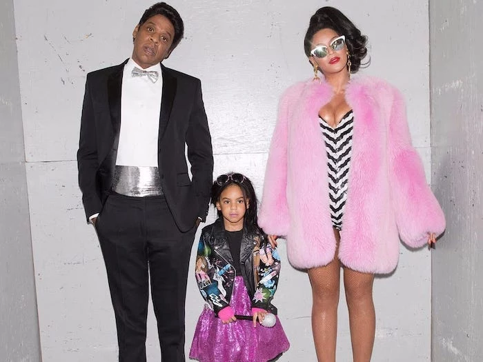 beyonce and jay z dressed as blue ivys barbie and ken family halloween costume ideas standing in front of white wall