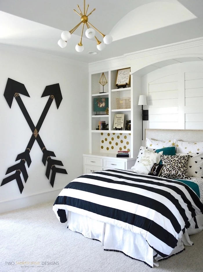 black arrows on white wall cozy teenage girl room bookshelves next to double bed with black white gold throw pillows
