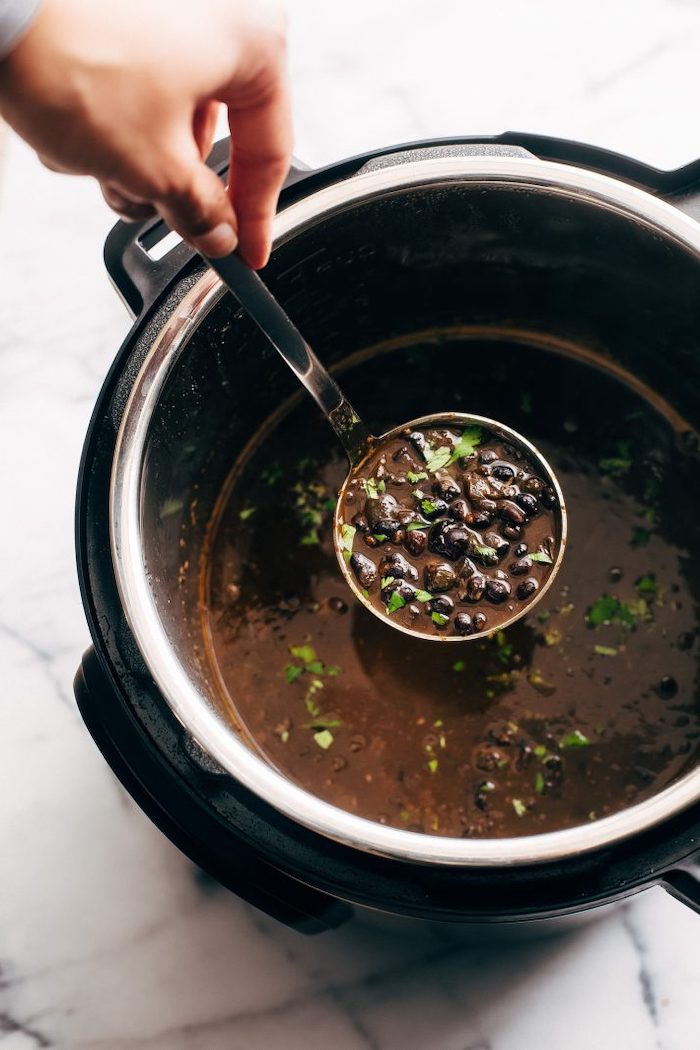 black bean soup garnished with chopped parsley instant pot one pot meals scooped with ladle