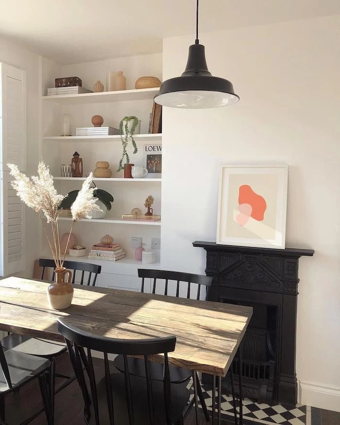 black fireplace artificial pampas grass inside ceramic vase placed on wooden table with black chairs