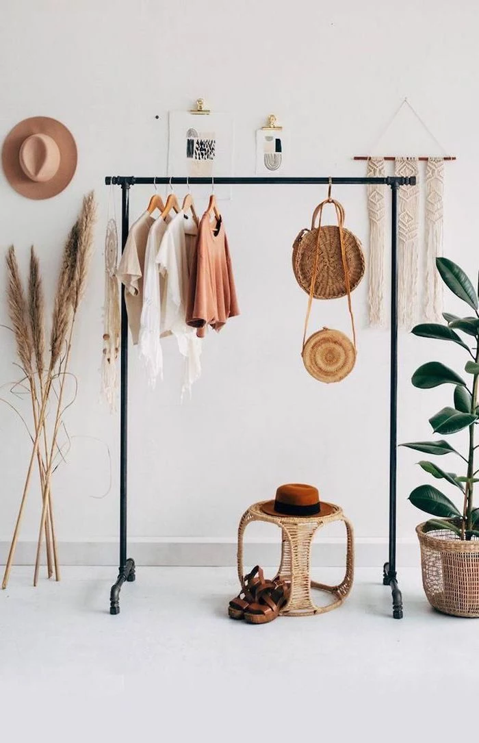 black metal railing with clothes hanging on it pampas grass leaning on the white wall next to it macrame hanging on the wall