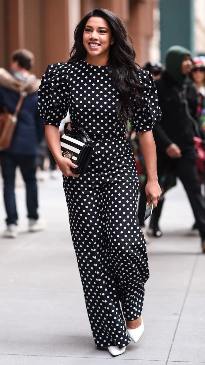 black onesie with white dots statement sleeves white shoes worn by woman with long black wavy hari outfit ideas for women walking down the street