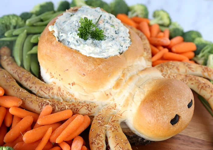 bread baked in the shape of spider with dip inside easy halloween appetizers baby carrots peas broccoli on the side