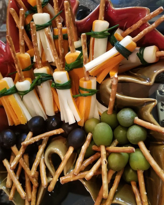 broomsticks made of crackers with cheese olives grapes arranged in ceramic bowl halloween appetizers