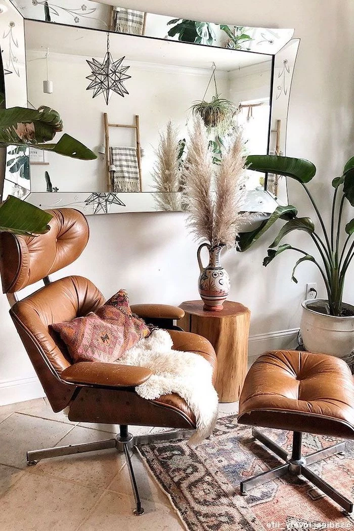 brown leather armchair ottoman small wooden vase next to it artificial pampas grass ceramic jug with pampas grass inside