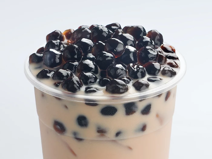 bubble tea with lots of boba tapioca pearls poured into plastic cup how to make boba white background
