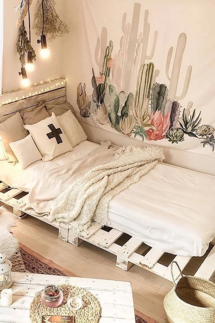 cozy teenage girl room sheet on white wall with cactuses drawn on it hanging above pallet bed wooden floor
