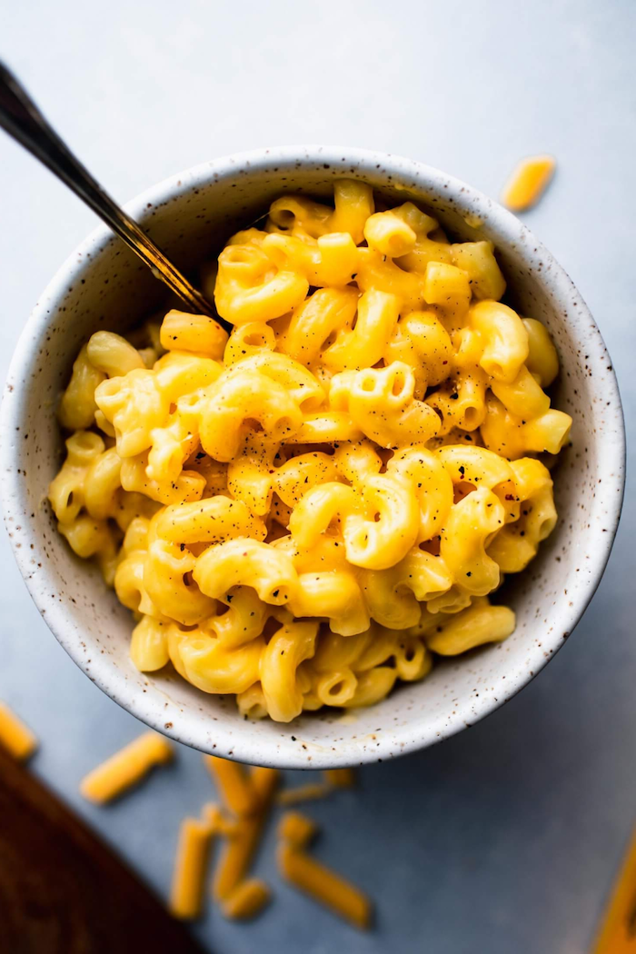 creamy mac and cheese with black pepper on top best pressure cooker recipes placed inside white ceramic bowl spoon on the side